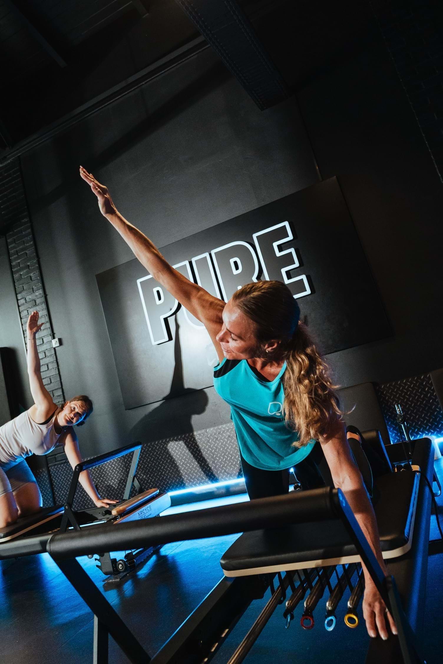 Member stretching their arm upwards during Reformer Pilates